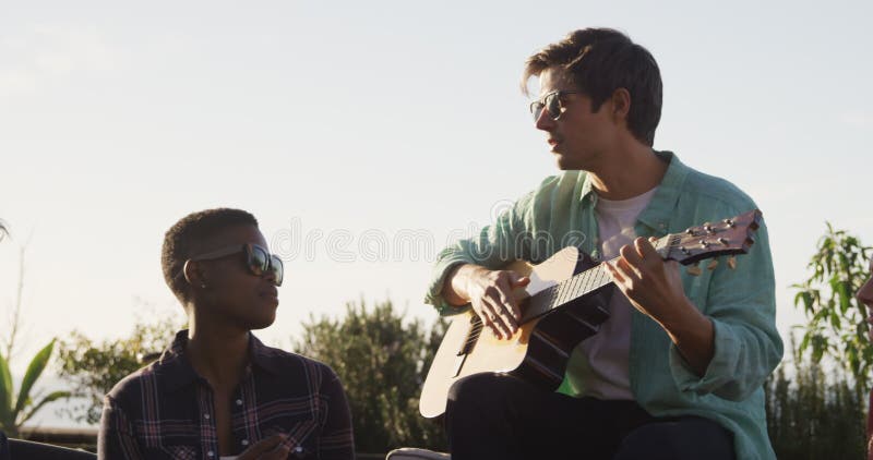 Un joven tocando guitarra en la azotea con sus amigos almacen de video