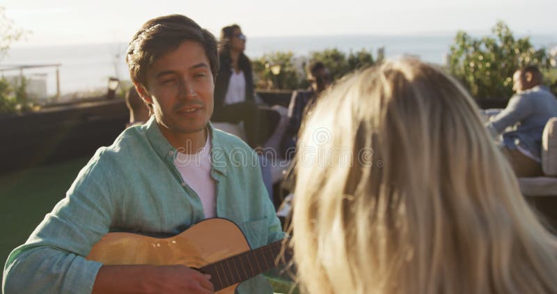 Un joven tocando guitarra en la azotea con sus amigos metrajes