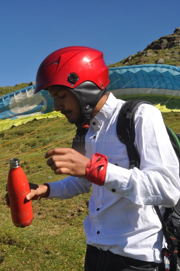 Un joven turista sostiene una botella de agua para beber antes de tomar un vuelo en parapente en la montaña de himachal pradesh fotos de archivo