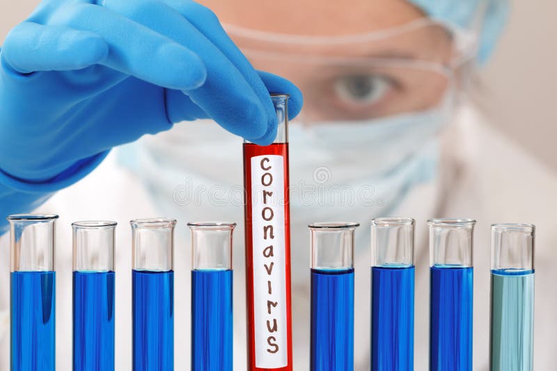 In un laboratorio di chimica, una ricercatrice femmina tiene un tubo di prova con il virus del coronavirus immagine stock In un laboratorio di chimica, una ricercatrice femmina tiene un tubo di prova con il virus del coronavirus immagine stock