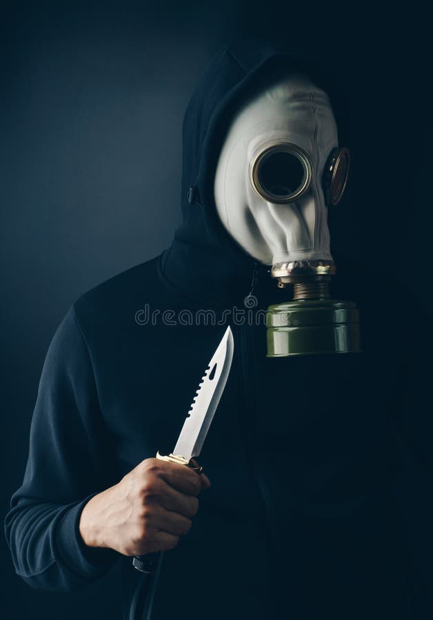 Un ladro spaventoso in maschera antigas con un coltello di combattimento immagine stock Un ladro spaventoso in maschera antigas con un coltello di combattimento immagine stock