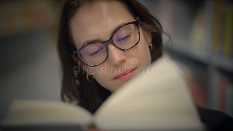Un lecteur ciblé, profondément engagé dans un livre intéressant, assis dans une bibliothèque banque de vidéos