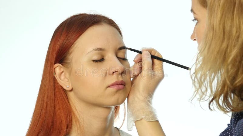 Un maquilleur professionnel dessinant les sourcils d'un beau client Le concept de beauté et de mode