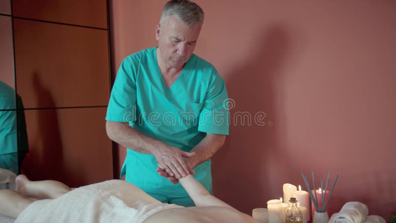 Un masajista terapeuta está tratando a una clienta sobre una mesa en un apartamento