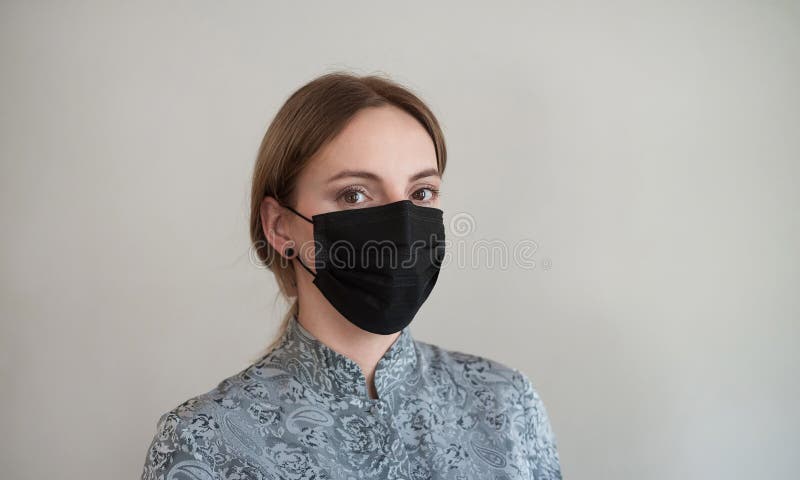 A medical mask on a woman `s face. Black mask to protect against bacteria, dust and viruses. Beautiful girl `s face behind a protective mask. A medical mask on a woman `s face. Black mask to protect against bacteria, dust and viruses. Beautiful girl `s face behind a protective mask