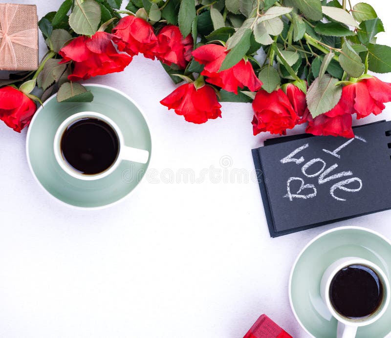 Un mazzo delle rose rosse e del tè aromatico fresco per le parole romantiche di una prima colazione di amore su una nota e su un. Un mazzo delle rose rosse e del tè aromatico fresco per le parole di una prima colazione di tic di amore su una nota e su un regalo con i fiori Concetto di festa della mamma e di San Valentino Disposizione piana c