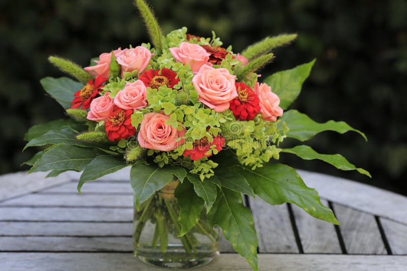 Un mazzo di fiori con le rose rosa, le hoste verdi e gli zinnias rossi fotografia stock Un mazzo di fiori con le rose rosa, le hoste verdi e gli zinnias rossi fotografia stock