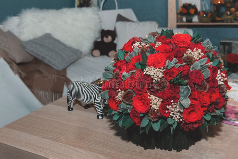Un mazzo enorme delle rose rosse è decorato nell'interno su una tavola di legno fotografia stock Un mazzo enorme delle rose rosse è decorato nell'interno su una tavola di legno fotografia stock