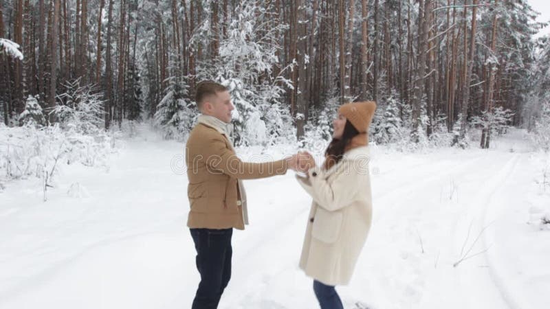 Un mec propose à une fille au milieu d'une forêt enneigée de s'embrasser et de tourner joyeusement dans la neige banque de vidéos