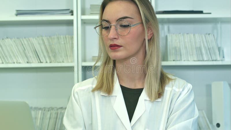 Un medico attraente in bicchieri con un portatile seduto alla reception