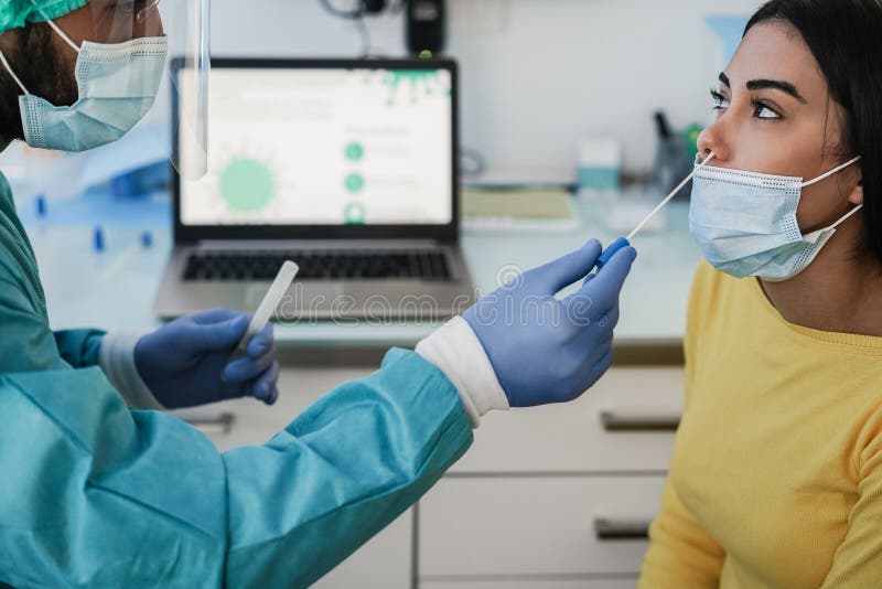 Doctor making swab nasal test to young woman in medical clinic for possible coronavirus infection - Focus on the right face. Doctor making swab nasal test to young woman in medical clinic for possible coronavirus infection - Focus on the right face