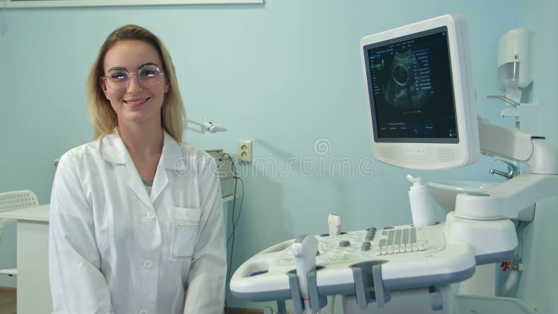 Un medico sorridente in bicchieri che guarda la telecamera in una stanza a ultrasuoni