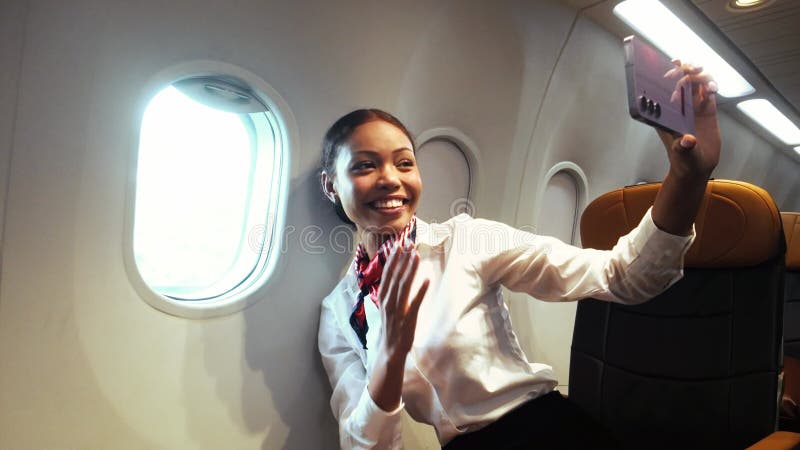 Un membre de l'équipage de cabine prend un selfie joyeux près de la fenêtre de l'avion qui présente le style de vie de voyage WiFi banque de vidéos