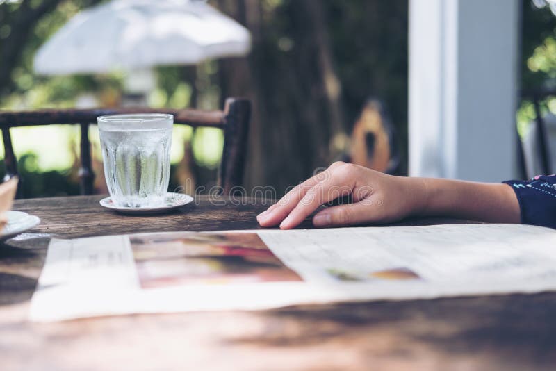 A woman sitting and reading menu on vintage wooden table in restaurant. A woman sitting and reading menu on vintage wooden table in restaurant