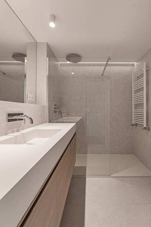 A modern bathroom with an elongated white faux stone sink with wooden cabinet underneath. A modern bathroom with an elongated white faux stone sink with wooden cabinet underneath
