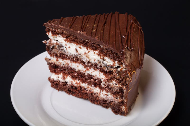 Un morceau de gâteau de chocolat du plat blanc sur le fond noir photos libres de droits Un morceau de gâteau de chocolat du plat blanc sur le fond noir photos libres de droits