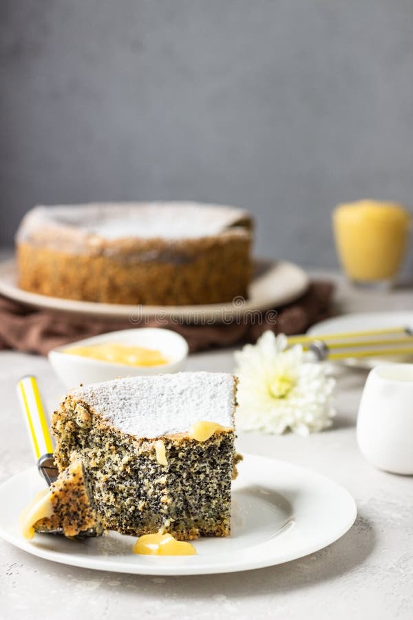 Un morceau de gâteau de graines de pavot avec du sucre en poudre, de la crème et une tasse de café photographie stock Un morceau de gâteau de graines de pavot avec du sucre en poudre, de la crème et une tasse de café photographie stock