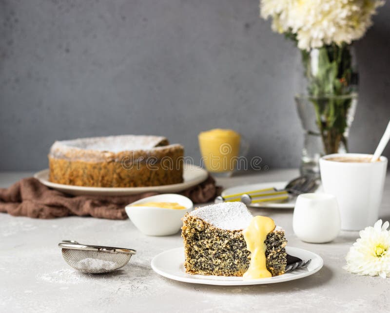Un morceau de gâteau de graines de pavot avec du sucre en poudre, de la crème et une tasse de café photographie stock libre de droits Un morceau de gâteau de graines de pavot avec du sucre en poudre, de la crème et une tasse de café photographie stock libre de droits