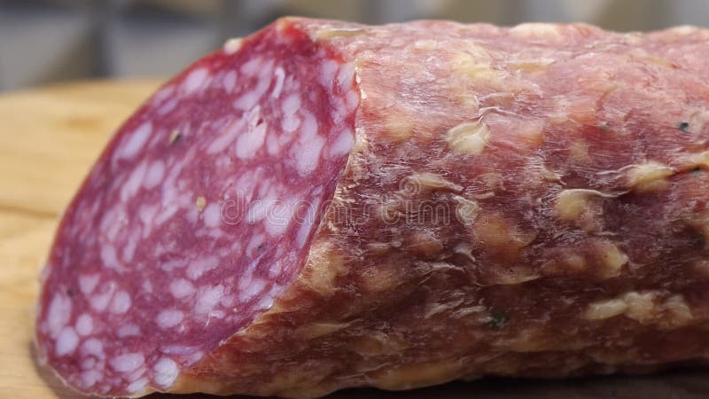 Un morceau de saucisse fumée sur une planche à découper en bois. macro vidéo. demi-saucisse banque de vidéos