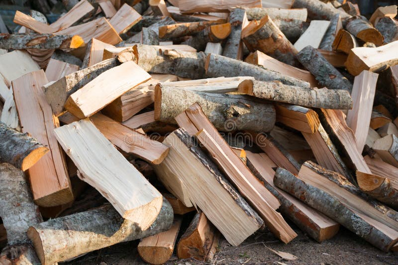 Un mucchio di legna da ardere tagliata si trova sulla terra Il materiale per riscaldare fotografia stock Un mucchio di legna da ardere tagliata si trova sulla terra Il materiale per riscaldare fotografia stock