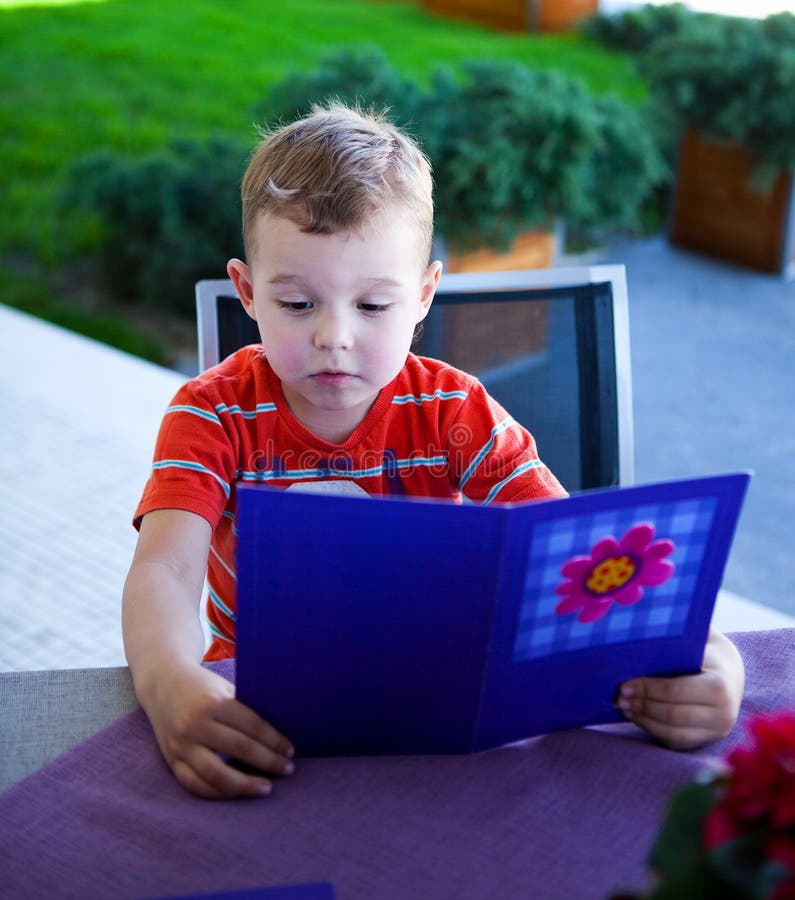 Little boy looking at a menu at a restaurant. Little boy looking at a menu at a restaurant