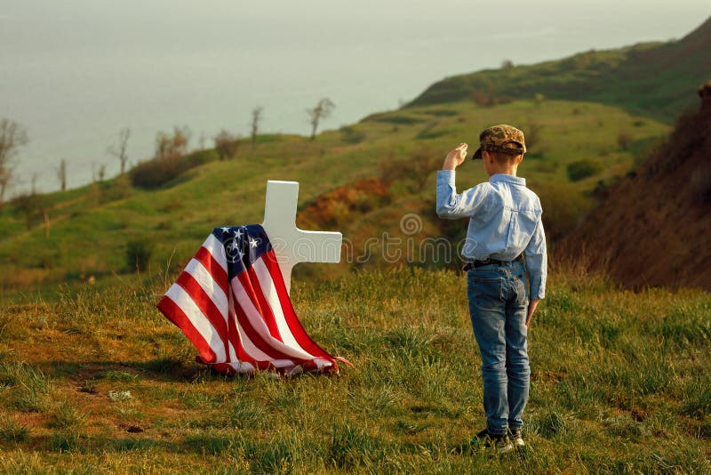 Un muchacho joven en un casquillo militar saluda el sepulcro de su padre el Memorial Day fotografía de archivo Un muchacho joven en un casquillo militar saluda el sepulcro de su padre el Memorial Day fotografía de archivo