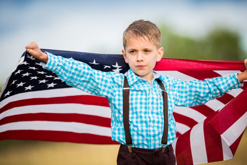 Un muchacho joven que sostiene la bandera americana que muestra el patriotismo para su propio país, une estados fotografía de archivo libre de regalías Un muchacho joven que sostiene la bandera americana que muestra el patriotismo para su propio país, une estados fotografía de archivo libre de regalías