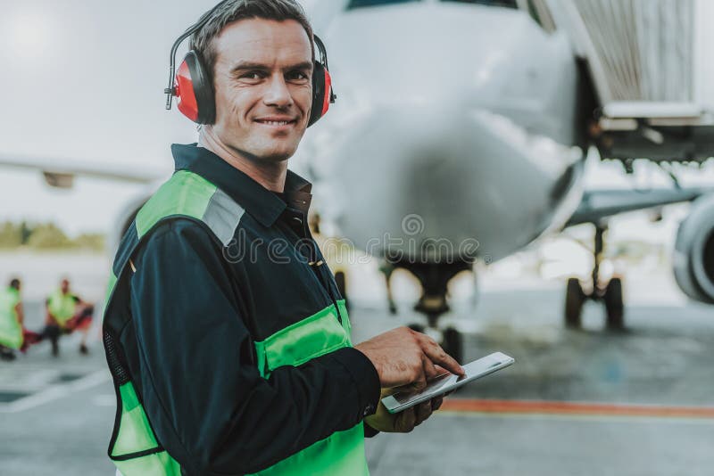 Un muncitor arătos care stă în fața unui avion uriaș stock image