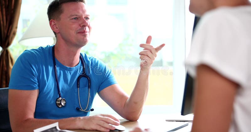 Un médecin mâle souriant communique avec une patiente à la clinique banque de vidéos