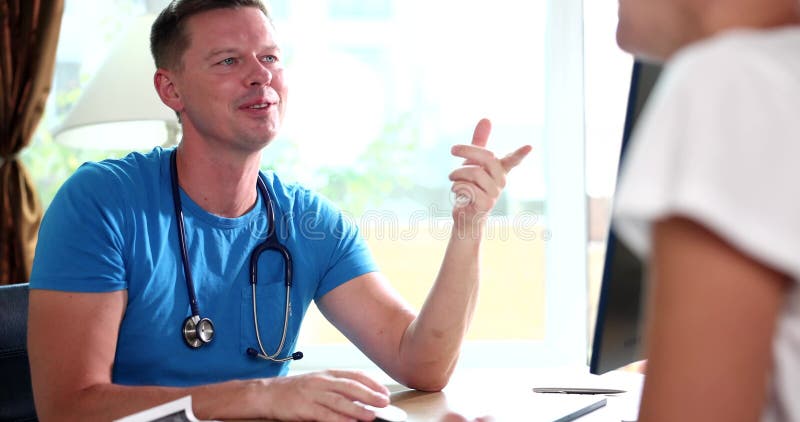 Un médecin mâle souriant communique avec une patiente à la clinique banque de vidéos