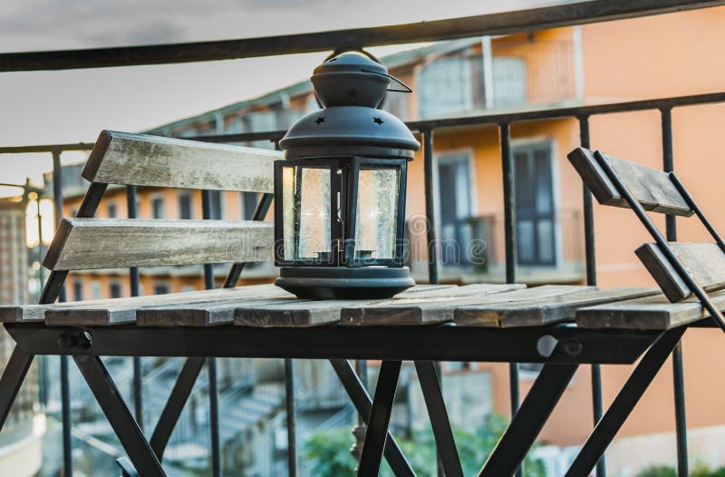 Un métal noir et une table grise en bois et deux chaises et un vieux chandelier en verre et en métal sur le balcon pendant le mat photo libre de droits Un métal noir et une table grise en bois et deux chaises et un vieux chandelier en verre et en métal sur le balcon pendant le mat photo libre de droits