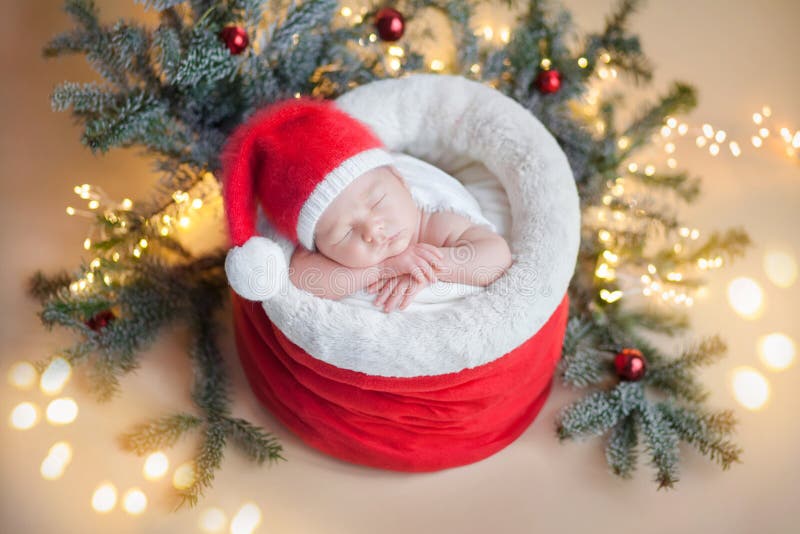 Un neonato col cappello di cremisi di uno gnomo nella borsa di Babbo Natale, intorno ai ramoscelli di Natale e alle palle di Nata fotografia stock libera da diritti Un neonato col cappello di cremisi di uno gnomo nella borsa di Babbo Natale, intorno ai ramoscelli di Natale e alle palle di Nata fotografia stock libera da diritti