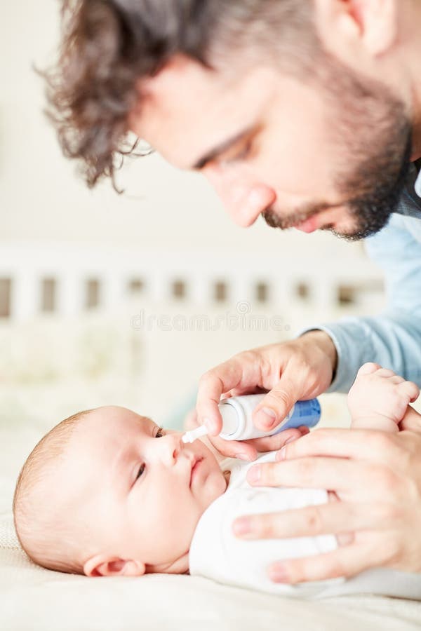 Sick baby gets nasal spray for cold from worried father. Sick baby gets nasal spray for cold from worried father