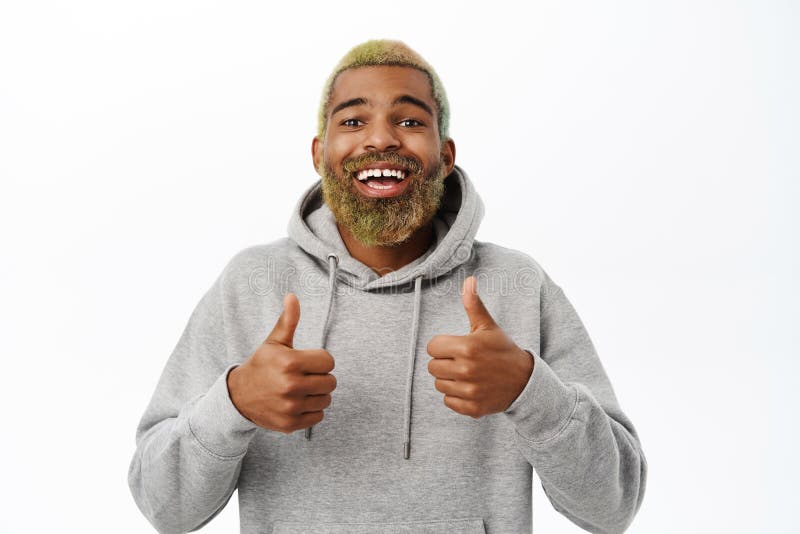 Un nero entusiasta con la barba che sorride e le risate che mostra i pollici approvare qualcosa di buono che consiglia fotografie stock
