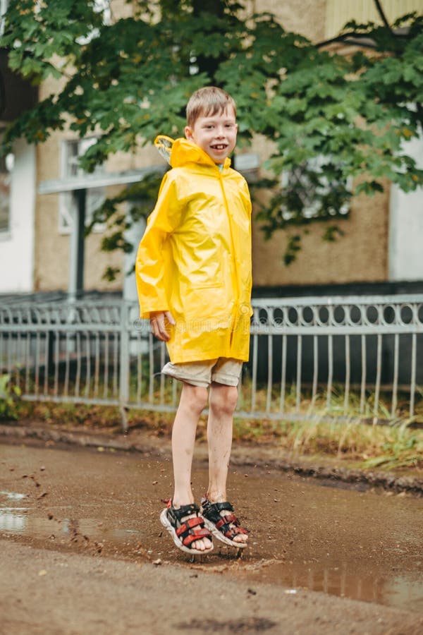 Un Niño Con Impermeable Amarillo Sale a La Lluvia. Solo Un Niño Camina Bajo  La Lluvia. Vista Posterior En Un Impermeable Brillante Imagen de archivo -  Imagen de cabritos, charco: 224329095