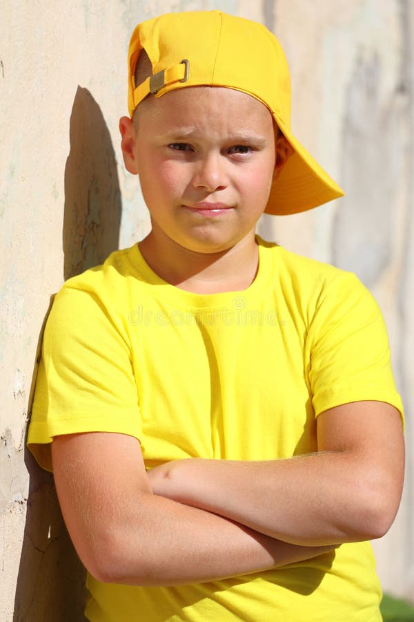 Un Niño Con Una Camiseta Amarilla Y Una Gorra Amarilla Se Pone Contra La  Pared En Verano Bajo El Sol Brillante Foto de archivo - Imagen de ropas,  confidente: 227287304