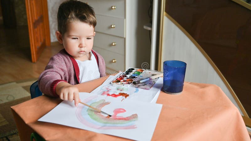 Un Niño De 2 Años Dibuja Un Arcoíris Con Pinturas. Actividades Creativas En  Casa Concepto. Pupitre De Niños Foto de archivo - Imagen de cabrito, lindo:  215087958