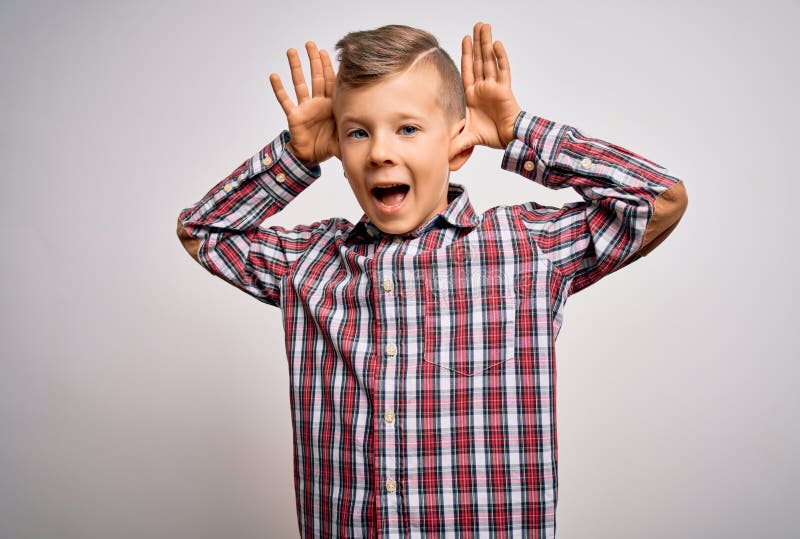 Un niño caucásico joven con los ojos azules y una camisa elegante sobre un fondo aislado sonriendo alegre jugando a lucir imágenes de archivo libres de regalías