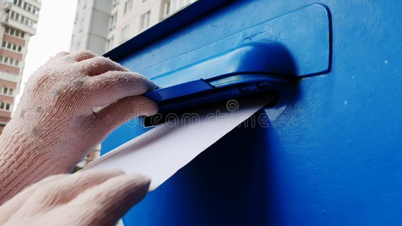 Un niño con guantes lanza una carta en una caja de correo azul.