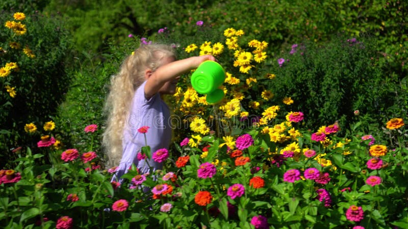 Un niño con un pequeño riego puede regar las flores en el patio. jardinero joven