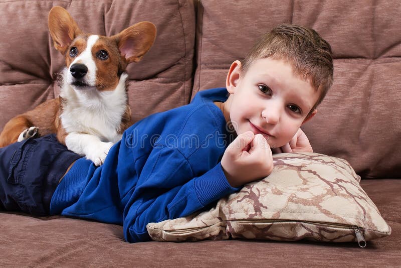 Un niño con un perro está tumbado en el sofá imágenes de archivo libres de regalías