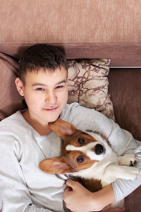 Un niño con un perro está tumbado en el sofá fotografía de archivo libre de regalías