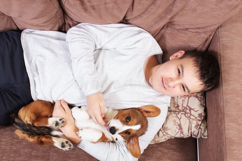 Un niño con un perro está tumbado en el sofá imágenes de archivo libres de regalías