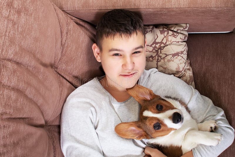 Un niño con un perro está tumbado en el sofá imágenes de archivo libres de regalías