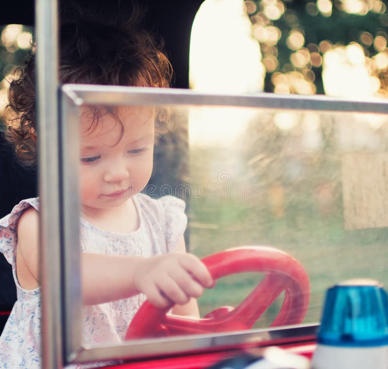 Un niño detrás de la rueda de un coche del juguete Niña pequeña en el parque de atracciones del carrusel foto de archivo Un niño detrás de la rueda de un coche del juguete Niña pequeña en el parque de atracciones del carrusel foto de archivo
