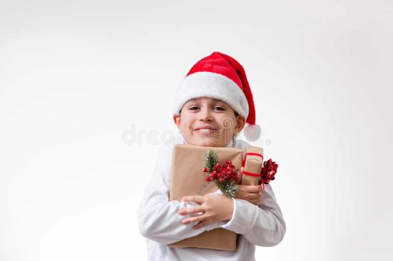 Un niño en cajas rojas de las sonrisas y los abrazos de un sombrero de santa de regalos. Concepto de Navidad imágenes de archivo libres de regalías