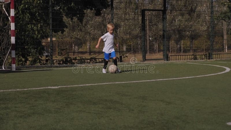 Un niño pequeño entrena en el campo de fútbol practicando balbuceo y fintas. almacen de metraje de vídeo