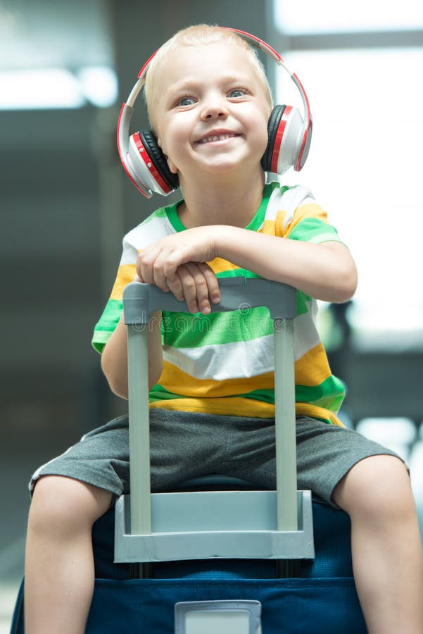 Un niño pequeño se sienta en la maleta grande en el aeropuerto Esperar el vuelo fotos de archivo Un niño pequeño se sienta en la maleta grande en el aeropuerto Esperar el vuelo fotos de archivo