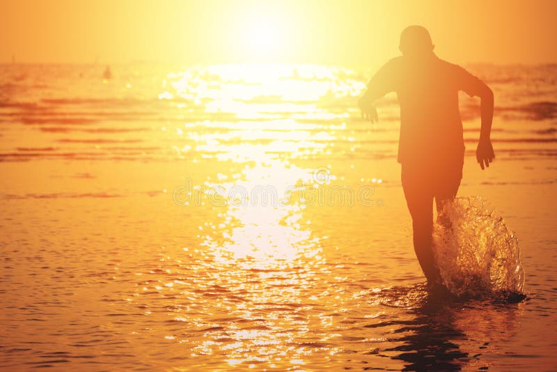 Un niño que corre al chapoteo del mar y del agua en verano con puesta del sol imágenes de archivo libres de regalías Un niño que corre al chapoteo del mar y del agua en verano con puesta del sol imágenes de archivo libres de regalías
