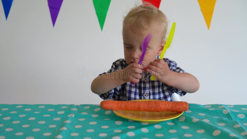 Un niño travieso tira la zanahoria del plato junto a la mesa. disparo en movimiento de truco.